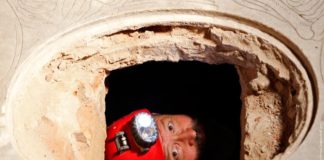 Researcher looks up out of tomb opened in stone church floor above family crypt of Florentine merchant del Giocondo at Santissima Annunziata basilica in Florence